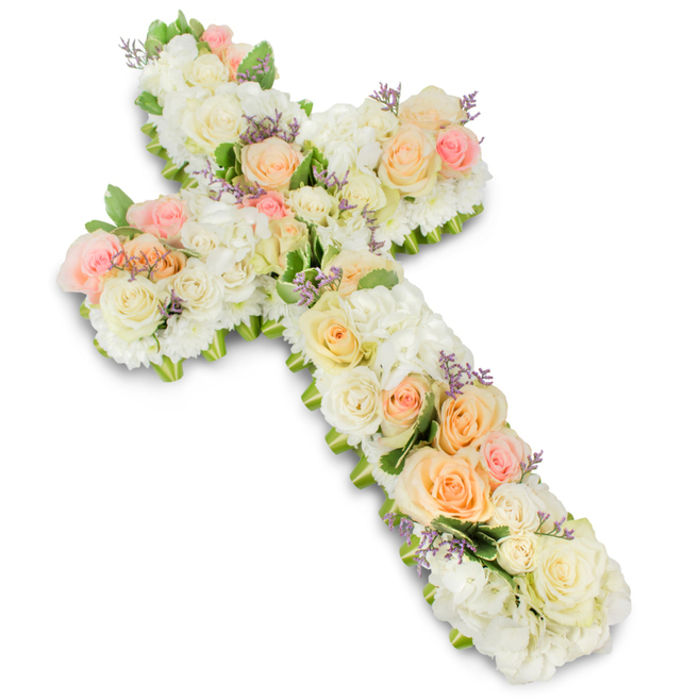 Displayed against a pristine, high-key white background, a beautifully detailed floral cross serves as the sole focus of the image, inviting a lingering look at every petal. The Christian cross shape is perfectly proportioned, its arms and central column densely covered in fresh blooms so that the arrangement appears lush, almost opulent, without ever feeling overwhelming. Large, premium roses in white, ivory, soft peach, and pale blush pink anchor the design, their full, cupped heads creating soft islands of colour that draw the eye along the length of the cross. They are supported by masses of white hydrangeas or similar multi-petalled flowers, whose fluffy, clustered heads add body and a pillowy texture, filling in every gap and creating a sense of comforting abundance. Scattered delicately throughout are tiny specks of lavender or light purple filler flowers, perhaps statice, offering a hint of cool contrast that gives the palette a luminous quality. Subtle sprays of fresh green foliage tuck in at the edges and between blossoms, outlining the cross with a natural frame and suggesting the living garden from which these flowers were cut. The lighting is soft and even, with a faint, diffused shadow under the arrangement for depth, but no harsh contrasts, echoing the gentle emotion of the piece. This is the kind of floral cross a family in Bounds Green might select for a funeral service at a local church or crematorium, expertly arranged by Bounds Green Flowers to sit beside a casket or near the altar. It conveys quiet faith, heartfelt sympathy, and lasting remembrance, making it a dignified and touching tribute for a final farewell.