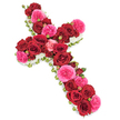 A beautifully composed sympathy cross made entirely of fresh flowers is presented against a bright white background, its colours and structure standing out with dignified clarity. The cross shape is completely filled with roses, the majority being deep, velvety red blooms that are fully open and densely packed together, forming a rich, almost tapestry-like surface. Between them, clusters of vivid fuchsia pink roses or similar garden-style varieties weave through the design, their softer, ruffled petals adding radiance and a comforting warmth to the solemn form. Smaller rosebuds in matching shades peek out here and there, providing texture and suggesting the many stages of a life remembered. Around the perimeter of the cross runs a neat band of tiny pure white flowers, likely spray chrysanthemums or delicate carnations, which create a soft halo effect and clearly define the traditional Christian outline. Slender green foliage and the faint suggestion of ribbon can be glimpsed at the very edges, hinting at the skilled framework and professional care behind the arrangement. The lighting is gentle and balanced, evoking the quiet calm of a chapel or funeral parlour in Bounds Green, perhaps just off Bounds Green Road or near the green spaces that families pass on the way to a service. This floral cross is the kind of tribute chosen for funerals, wakes, or memorials, where loved ones gather to honour a life with beauty and reverence. It conveys messages of faith, remembrance, and deep affection, offering a serene, rose-filled emblem of goodbye.
